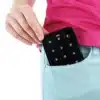 A woman is holding a portable red light panel in her pocket.